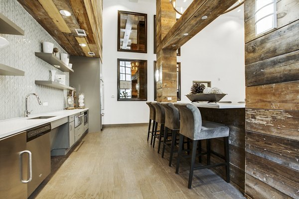 Stylish clubhouse bar at West Koenig Flats Apartments with modern seating and lighting, perfect for social gatherings and relaxation