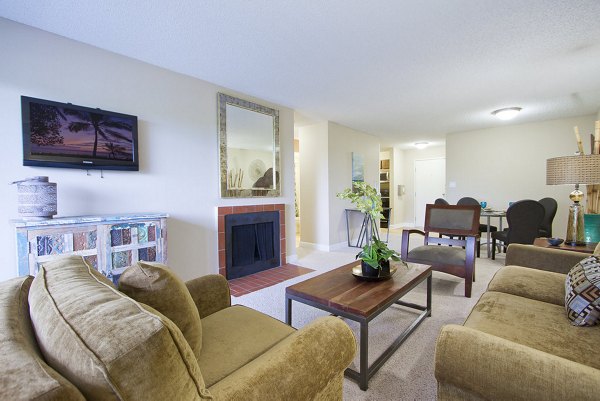 Cozy living room with fireplace, TV, and comfortable seating at Summit Ridge Apartments in a Greystar luxury community