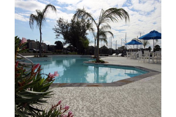 Scenic poolside view at CP Waterfront Apartments featuring modern lounge chairs and lush greenery