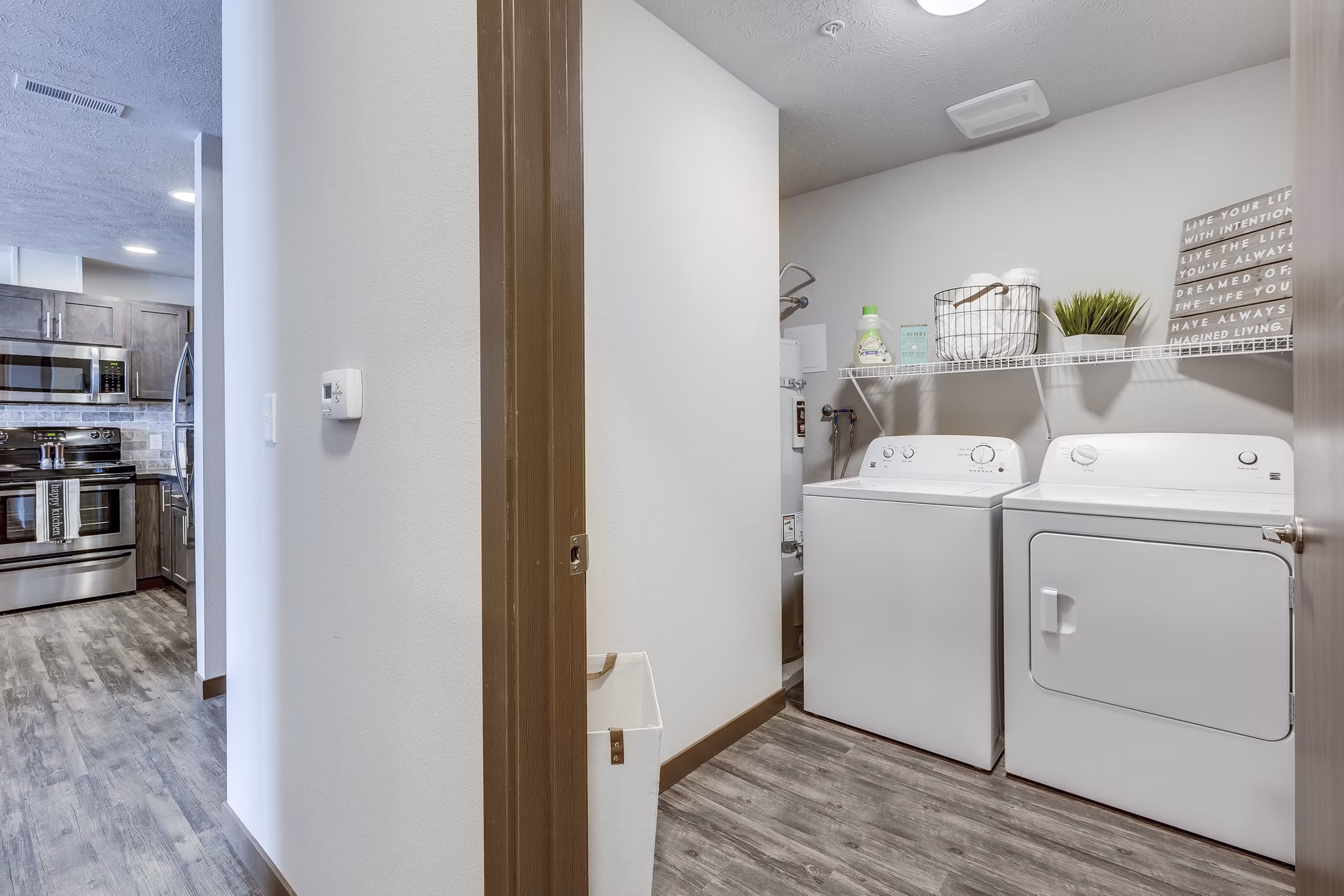 Laundry room with modern appliances at Bella Tess Apartments featuring ample countertop space and convenient shelving for storage