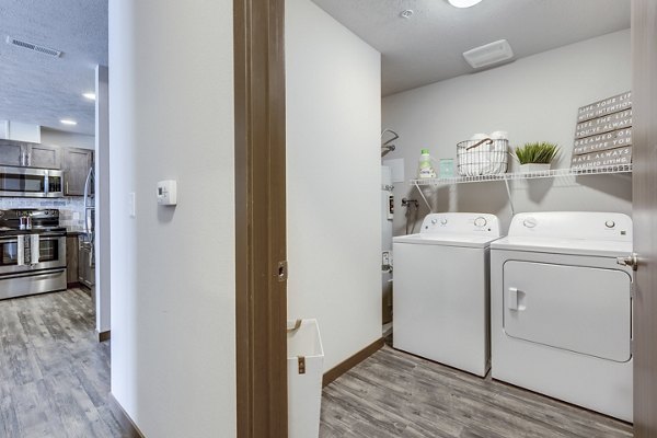 Laundry room with modern appliances at Bella Tess Apartments featuring ample countertop space and convenient shelving for storage