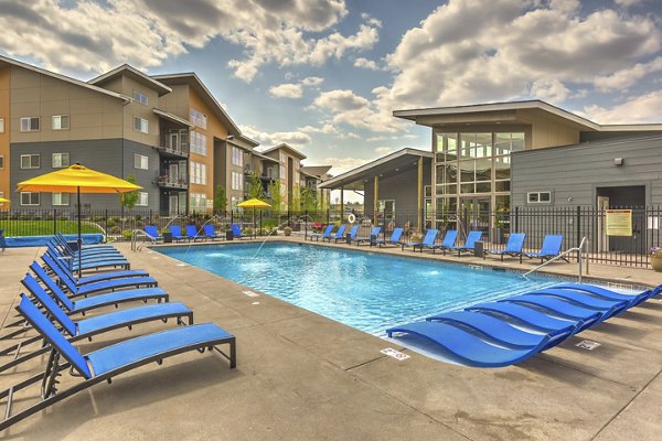Outdoor swimming pool at Bella Tess Apartments with lounge chairs and landscaped surroundings