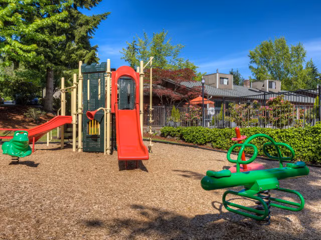 Playground at Onyx Apartments featuring colorful slides and swings, perfect for family fun in a community setting