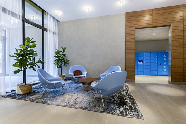 Modern lounge area with blue chairs, a round table, and plants in luxury apartments