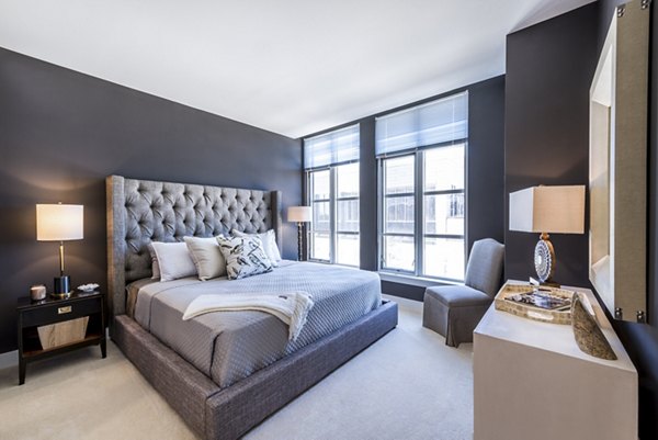 Modern bedroom featuring a large bed, stylish nightstands, and a cozy chair in luxury apartments