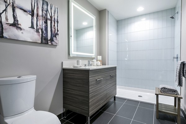 Modern bathroom featuring a stylish shower, sleek vanity, and decorative wall art in luxury apartment