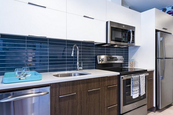 Modern kitchen with stainless steel appliances in Greystar luxury apartment, offering sleek countertops and ample storage for comfortable living