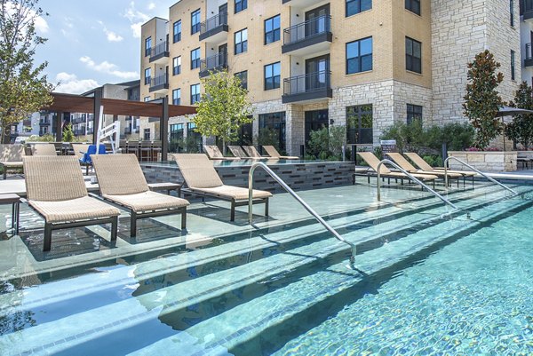 Infinity pool with lounge chairs at Overture Fairview Apartments