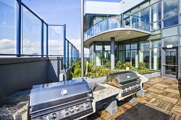 Modern outdoor grill area at Ascent Uptown Apartments with seating and city skyline views