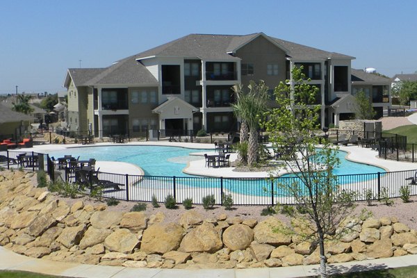 Relaxing poolside oasis at La Contessa Apartments with lush landscaping