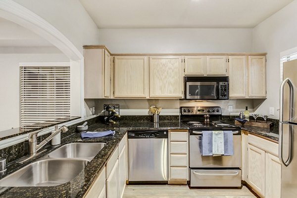 Modern kitchen with stainless steel appliances and quartz countertops at Riviera at West Village Apartments