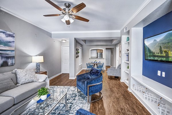 Spacious living room with modern decor and large windows in Riviera at West Village Apartments, offering luxury living near shopping districts