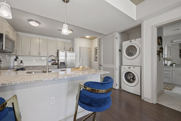Modern kitchen and laundry at Skyhouse Uptown North Apartments featuring stainless steel appliances and smart storage solutions