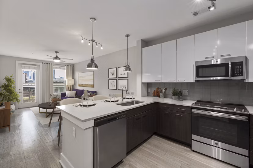 Warm, open-concept kitchen with stainless steel appliances at Cadence Music Factory Apartments