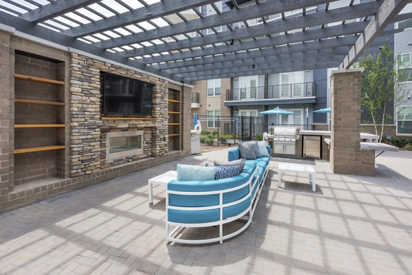 Rooftop deck with grill area and fire pit at Cadence Music Factory Apartments