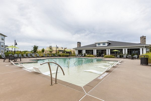 Modern pool area at Element Barclay Apartments with lounge chairs and lush greenery, offering luxury relaxation spaces for residents
