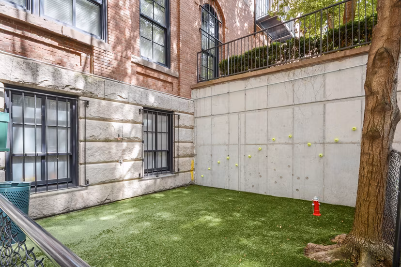 Off-leash dog park at James and Harrison Court Apartments featuring agility equipment and shaded seating areas