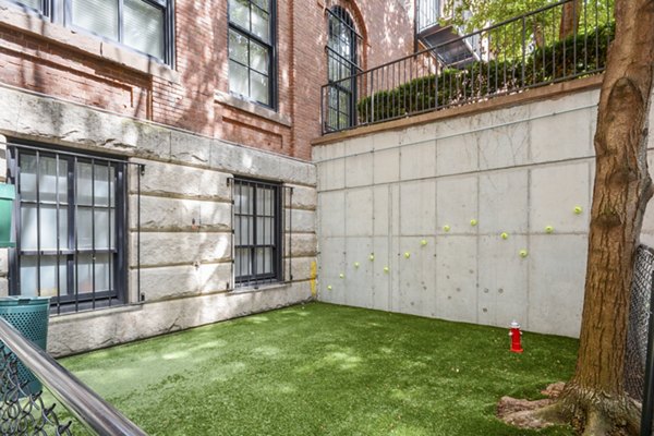 Off-leash dog park at James and Harrison Court Apartments featuring agility equipment and shaded seating areas