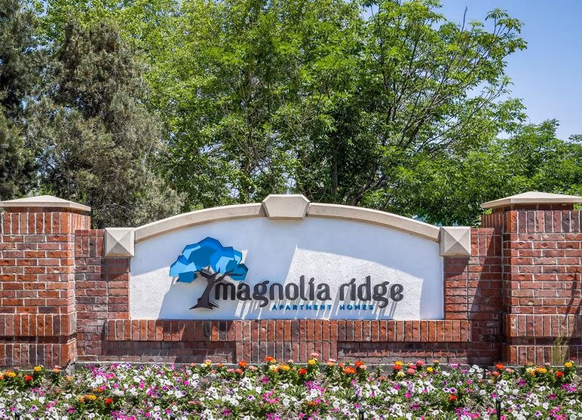 Magnolia Ridge Apartment Homes sign surrounded by vibrant flowers and lush trees