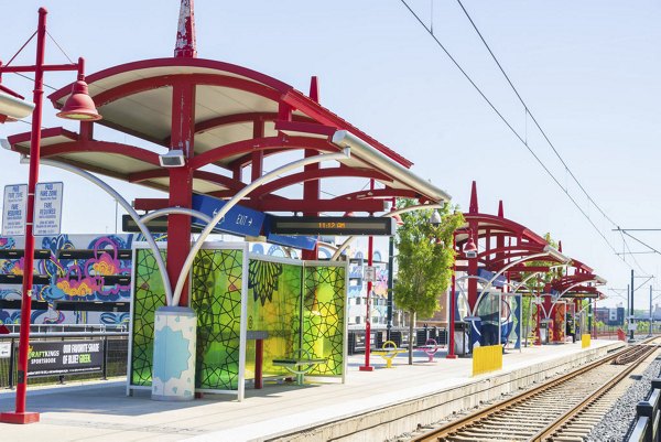 Colorful light rail station featuring red canopies and decorative panels in a vibrant urban setting