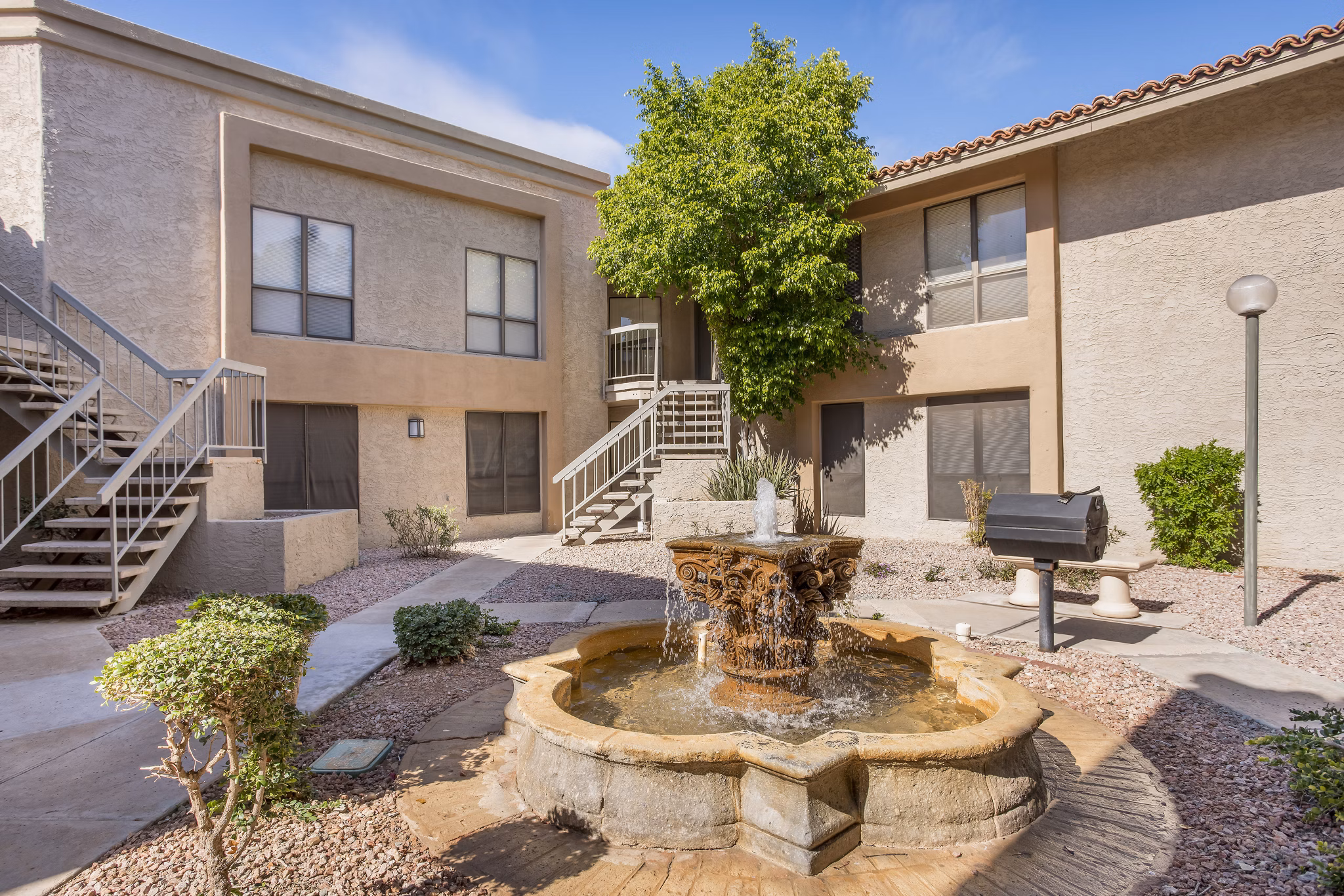 Outdoor grill area with seating and greenery at Avana at the Pointe Apartments, perfect for social gatherings and cookouts