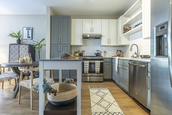 Contemporary kitchen with stainless steel appliances and granite countertops at The Sawyer Providence Farm Apartments