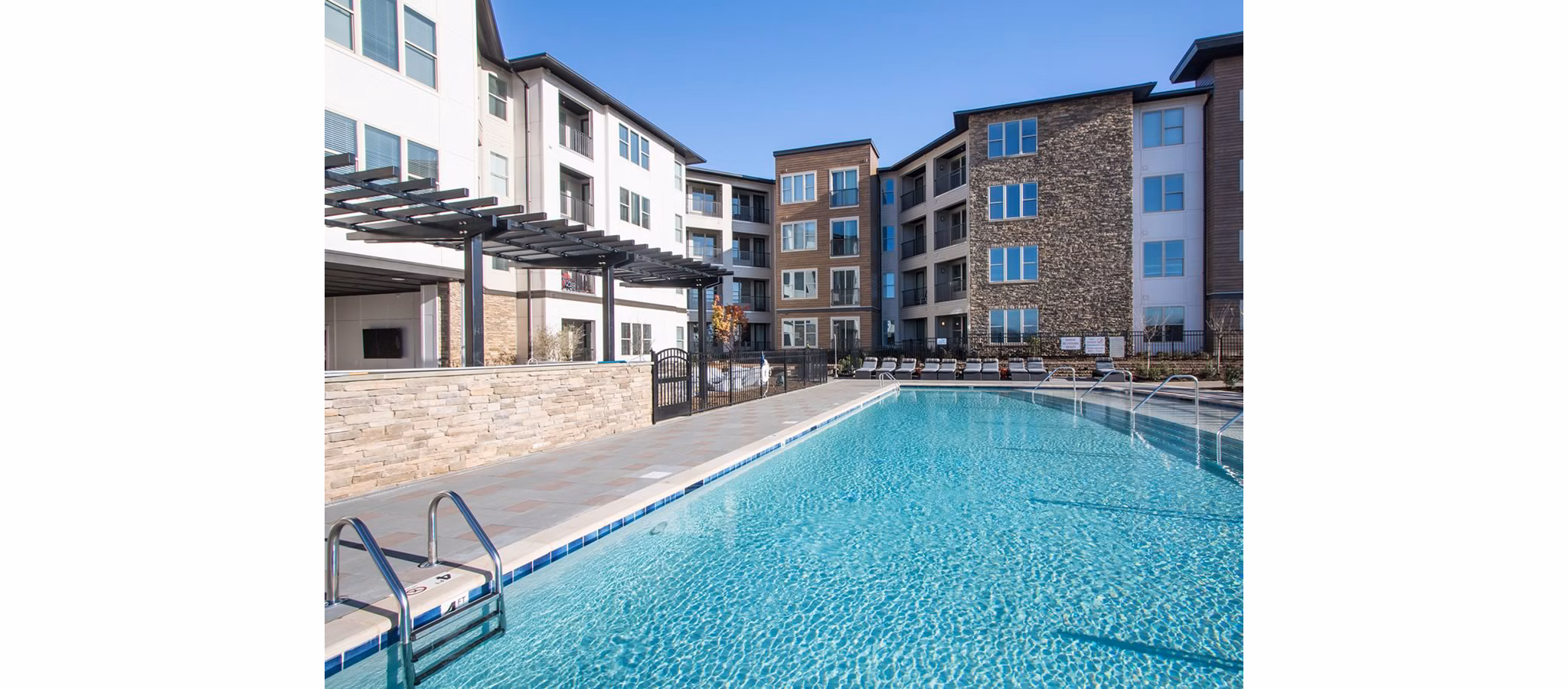 Poolside relaxation at The Sawyer Providence Farm Apartments with sun loungers and lush landscaping