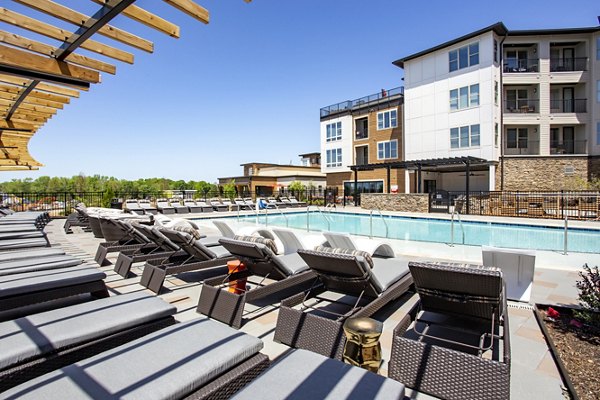 Poolside relaxation area at The Sawyer Providence Farm Apartments featuring lounge chairs and lush landscaping