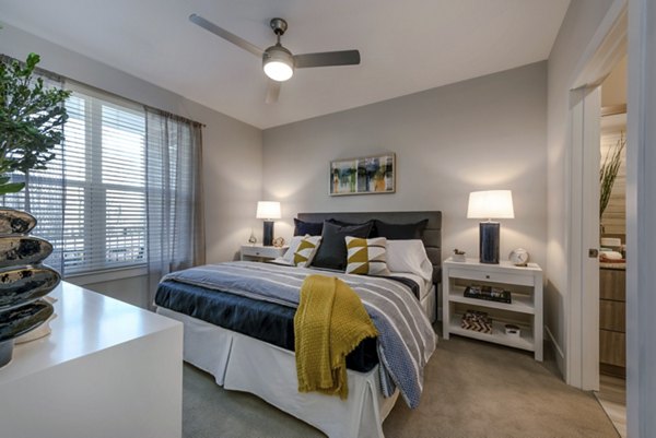 Modern bedroom featuring a cozy bed, stylish nightstands, and decorative artwork with natural light from a window