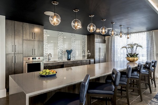 Modern kitchen featuring a long island with bar stools and pendant lights in luxury apartment
