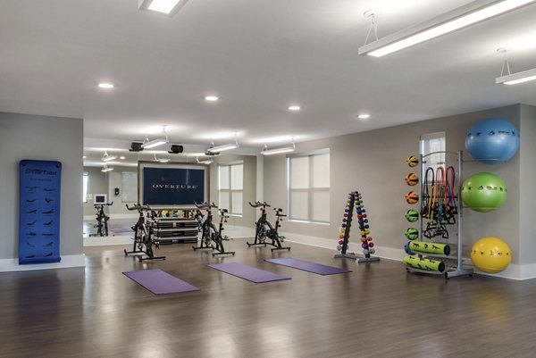Fitness room featuring stationary bikes, yoga mats, and weights in luxury apartments