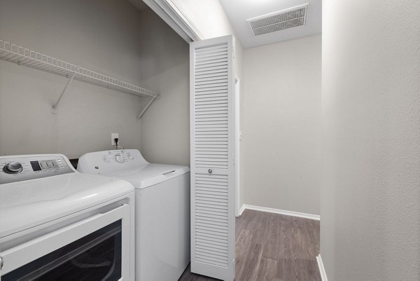 Laundry room featuring modern appliances at Cary Greens at Preston Apartments