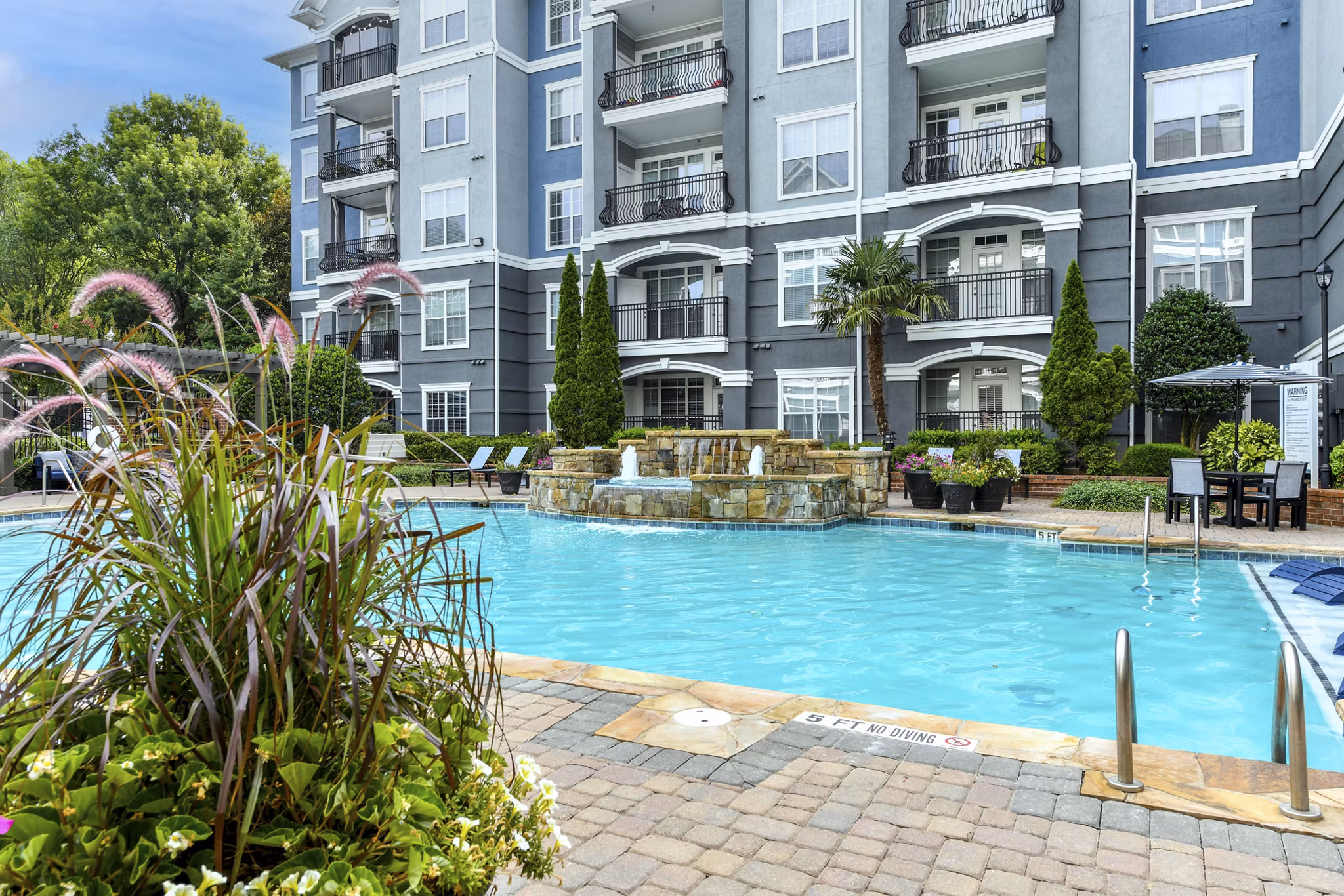 Outdoor swimming pool with lounge chairs at Avana City North Apartments