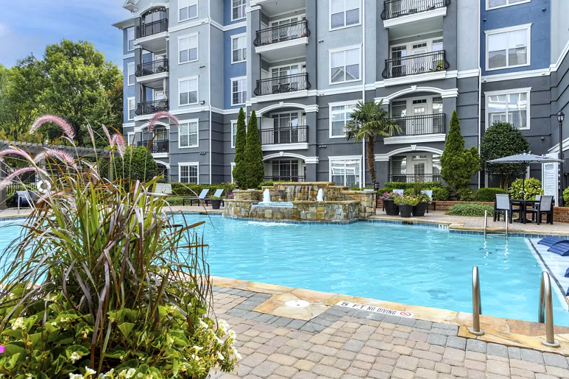Outdoor swimming pool with lounge chairs at Avana City North Apartments