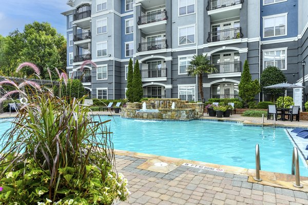 Outdoor swimming pool with lounge chairs at Avana City North Apartments