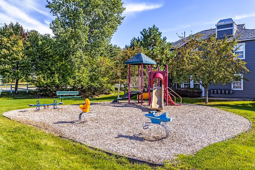 Colorful community playground at The Grand Reserve Apartments featuring swings and slides