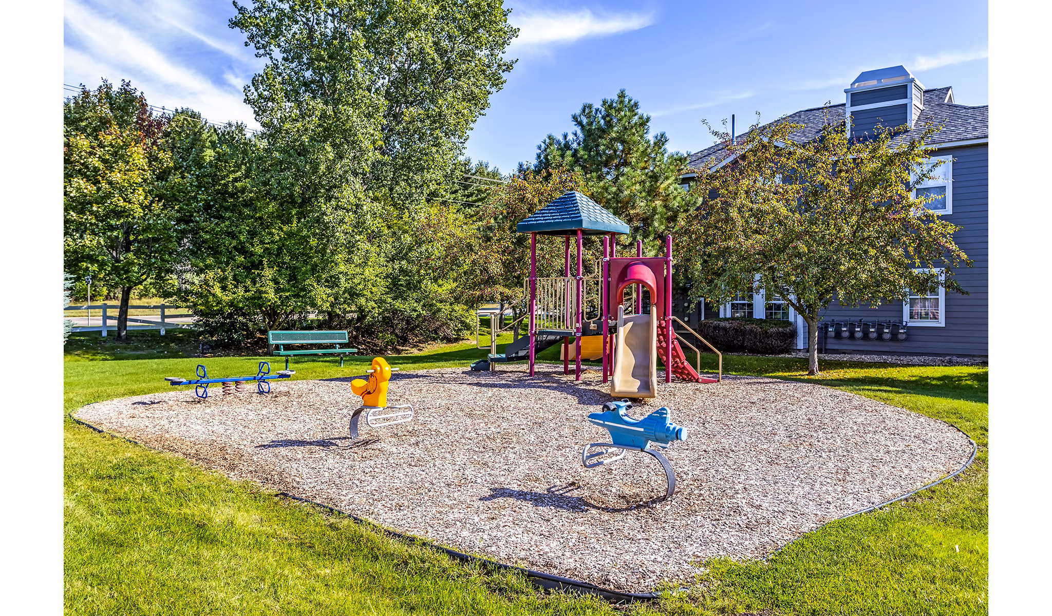 Colorful community playground at The Grand Reserve Apartments featuring swings and slides