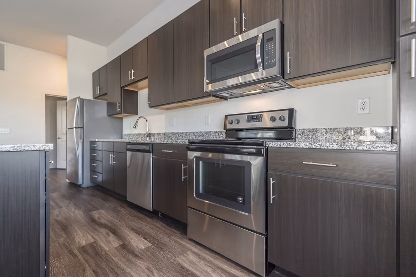 Modern kitchen with stainless steel appliances in Sunnen Station Apartments, featuring elegant cabinetry and open layout for luxury living