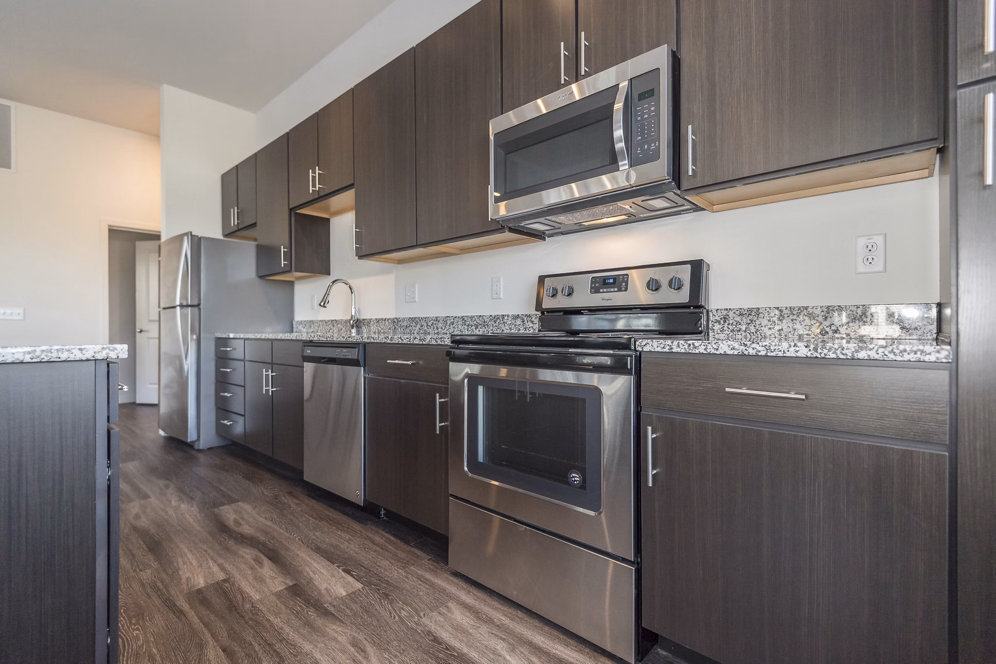 Modern kitchen with stainless steel appliances in Sunnen Station Apartments, featuring elegant cabinetry and open layout for luxury living