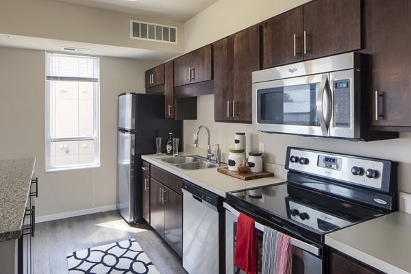 Modern kitchen with stainless steel appliances and granite countertops in Grain Belt Apartments