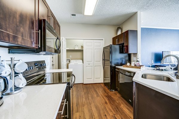Kitchen featuring modern appliances and laundry facilities at Commons at Briargate Apartments