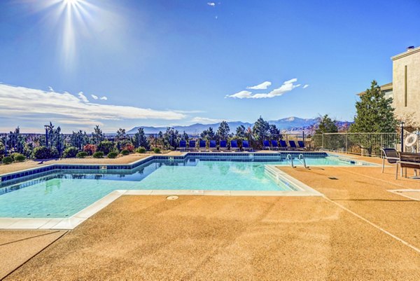 Relaxing pool area at Commons at Briargate Apartments with surrounding lounge chairs and scenic views