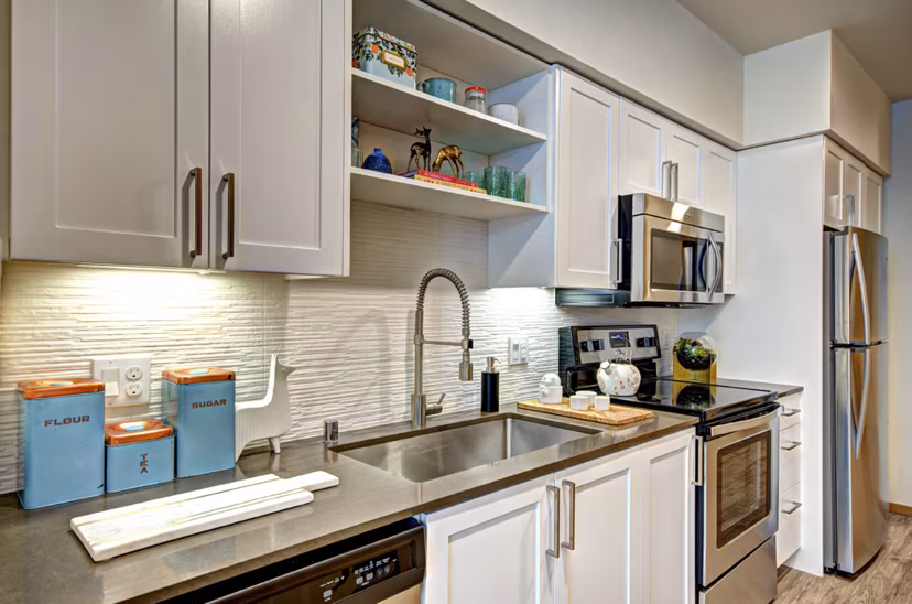 Modern kitchen with stainless steel appliances and granite countertops in Aura West Seattle Apartments