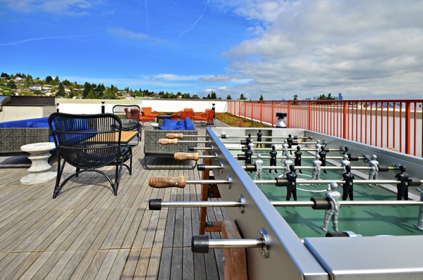 Outdoor rooftop games area at Aura West Seattle Apartments with city skyline views