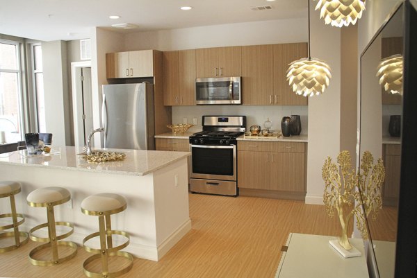 Spacious kitchen with modern appliances and breakfast bar at The Harper at Harmon Meadow Apartments