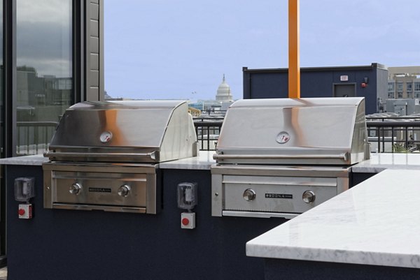 Outdoor grill area with seating at The Aspen Apartments, ideal for social gatherings and barbecues