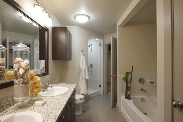 Modern bathroom featuring a double sink vanity, bathtub, and shower in luxury apartment