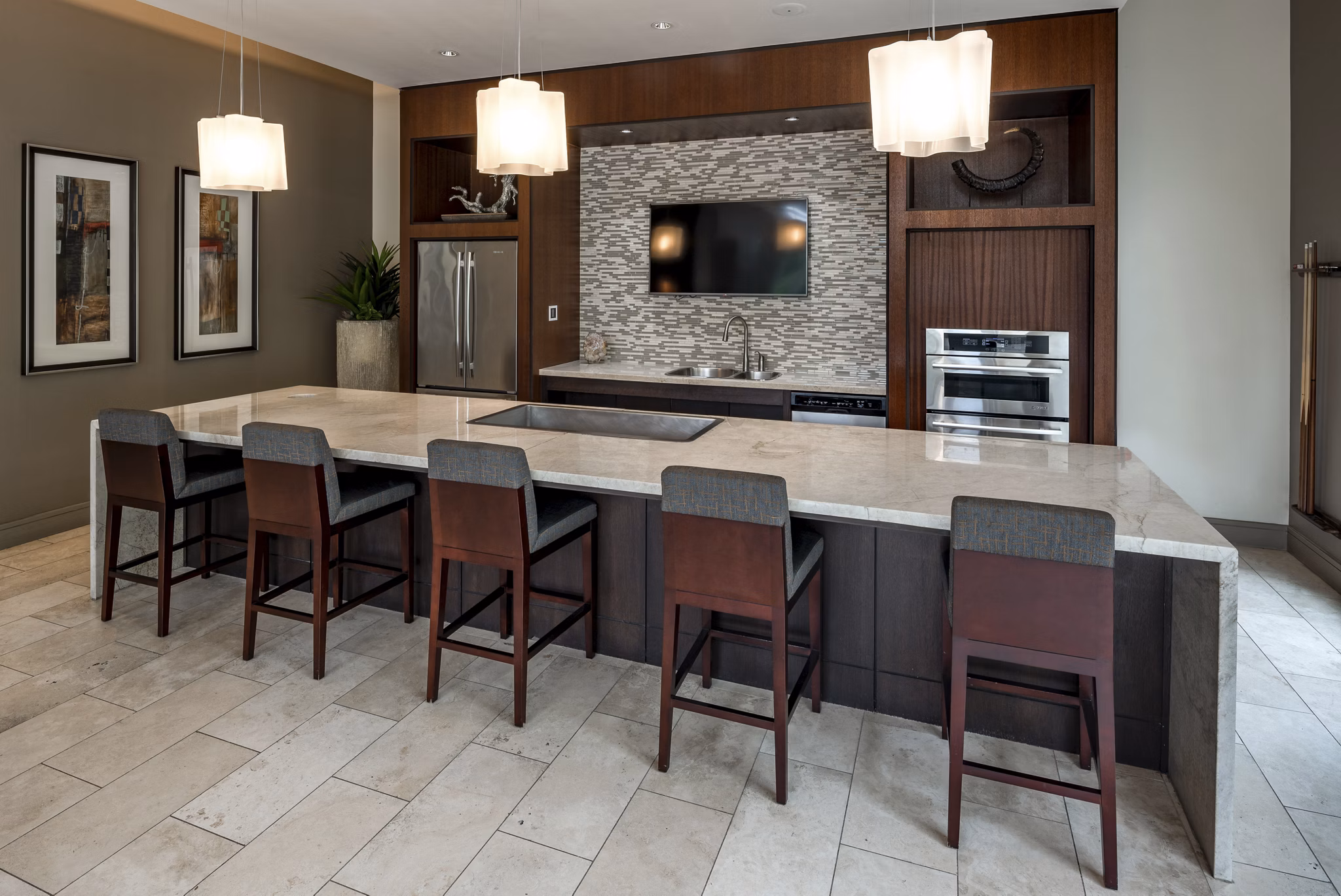 Modern kitchen featuring large island and bar stools with pendant lights and built-in appliances