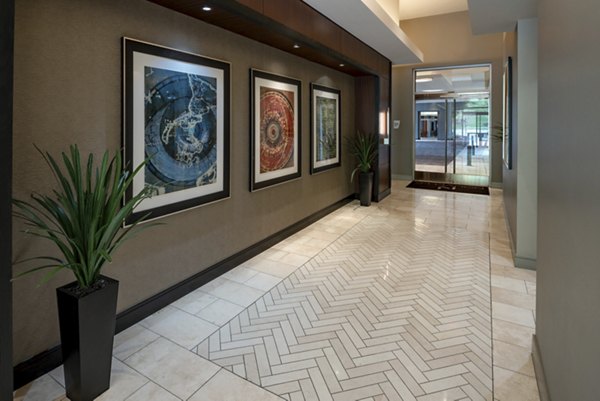 Elegant hallway with framed artwork, potted plants, and a tiled floor in luxury apartments