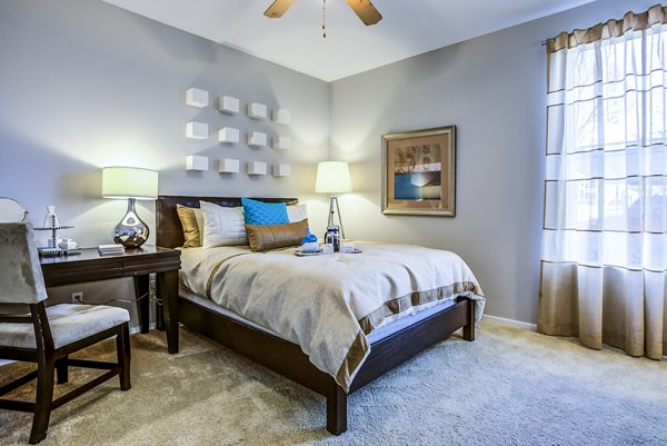 Bedroom with cozy decor featuring large windows at Acacia on Santa Rosa Creek Apartments